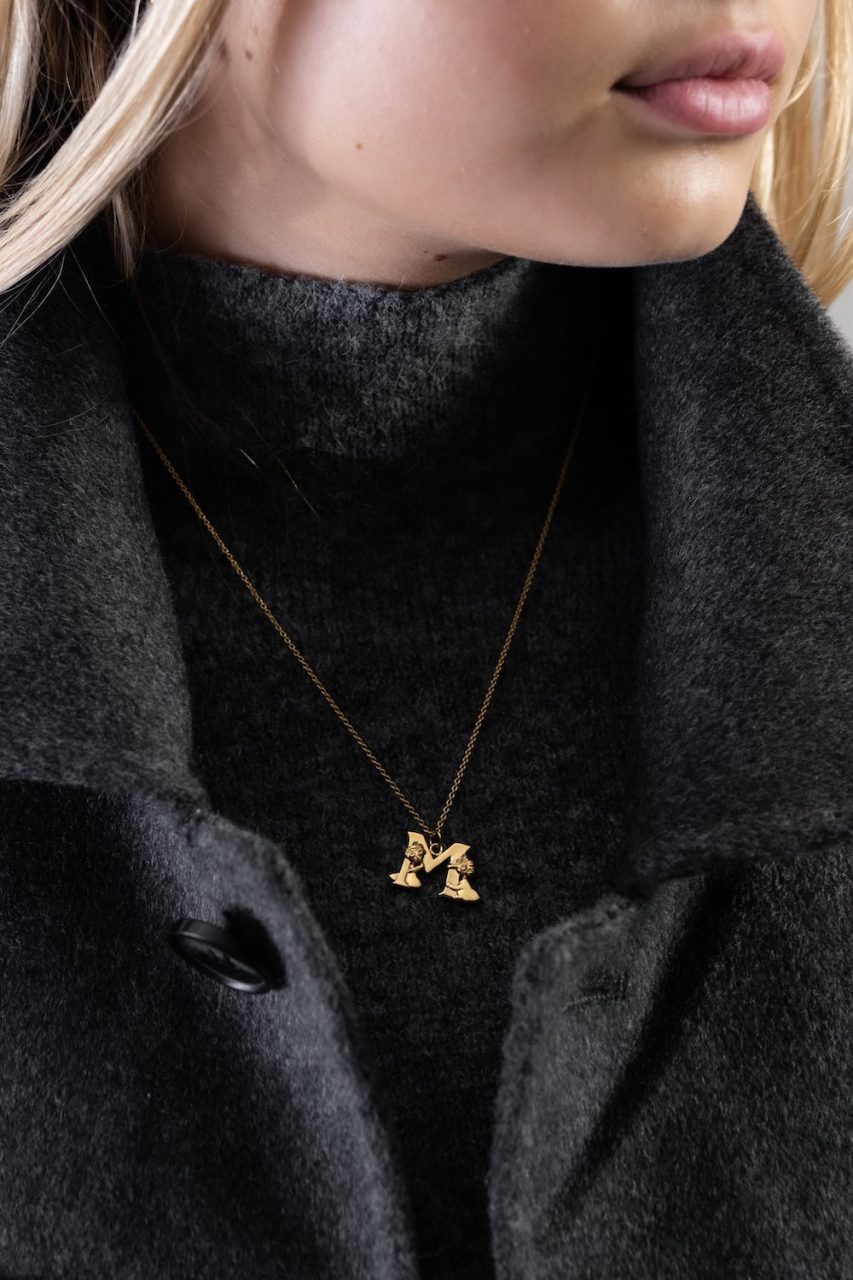 woman wearing letter M necklace